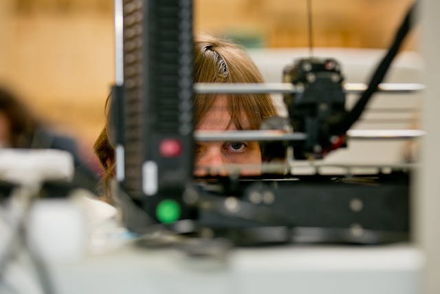 Portrait photo of Pavol Hejný looking behind of 3D printer